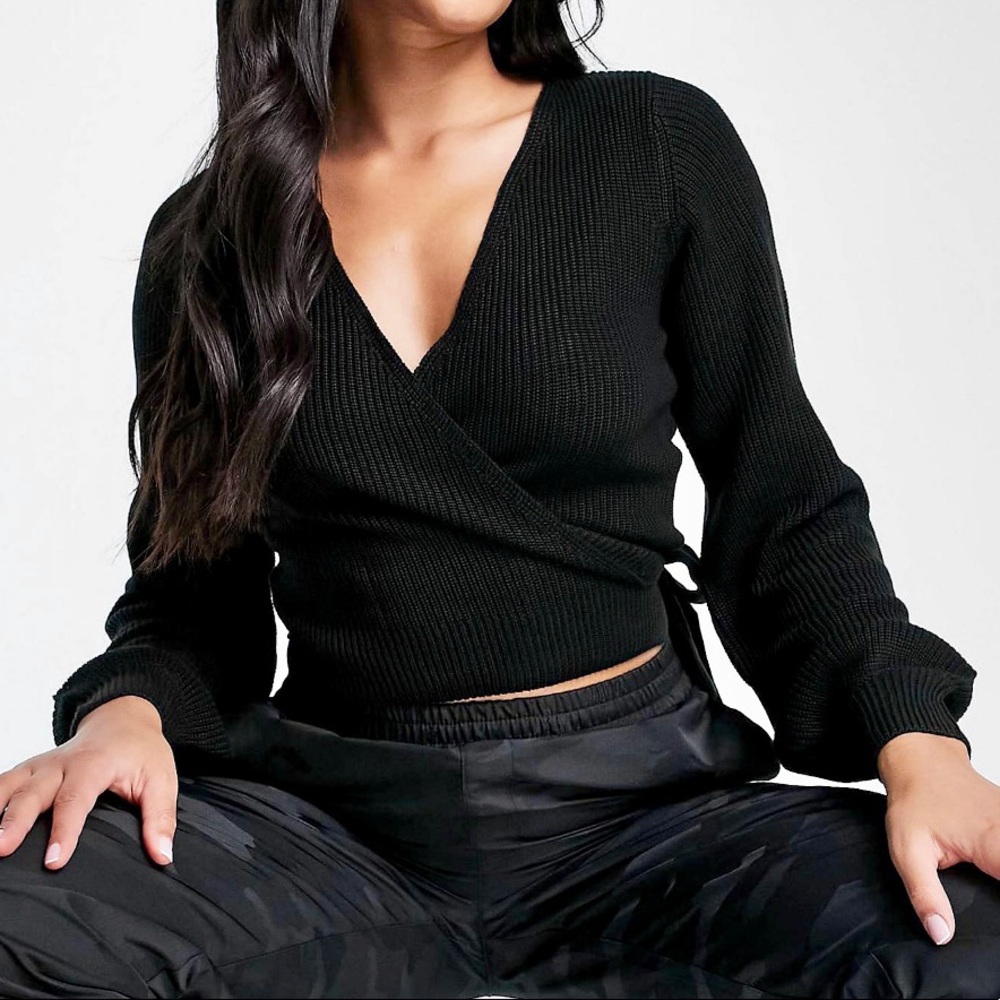 Wrap front ribbed sweater with balloon sleeves in black.